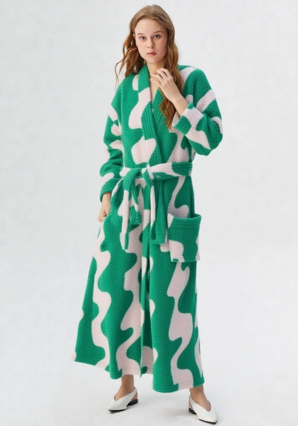 Femme portant robe de chambre polaire longue verte et blanche motifs abstraits avec ceinture et grandes poches plaquées, escarpins blancs