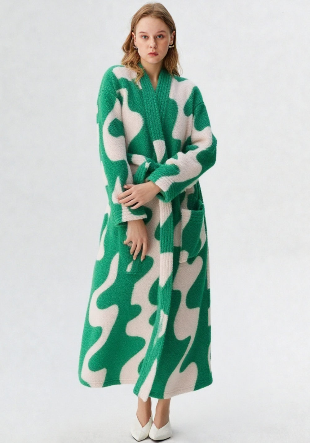 Femme de face en robe de chambre polaire longue verte et blanche à motifs abstraits, col V, sans capuche, escarpins blancs, longueur cheville