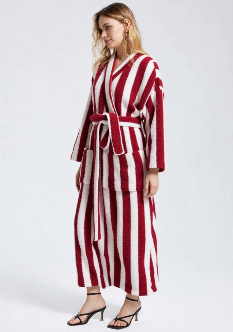 Femme de 3/4 portant une robe de chambre polaire longue à rayures verticales rouge et blanc, ceinture rouge, sandales à talons noires